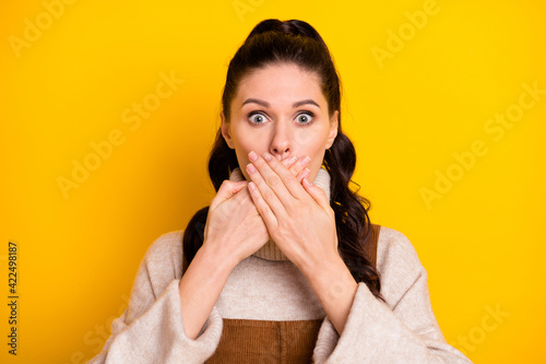 Portrait of attractive worried amazed girl closing mouth oops dont speak isolated over bright yellow color background