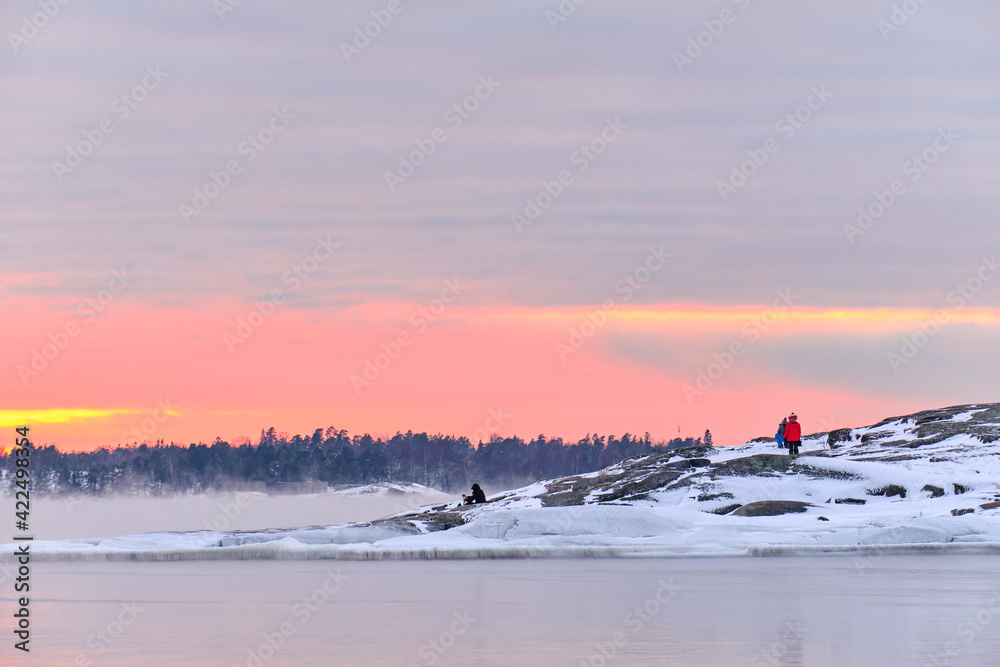 Ice-covered Baltic seashore in Finland. Fog over the sea during a strong frost in the sunset.