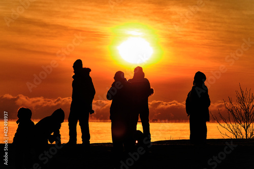 Obraz na płótnie Silhouettes of people on the background of an orange sunset over the sea w salonie