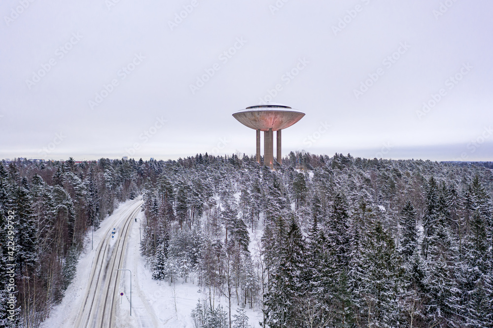 Espoo, Finland - February 1, 2021: Aerial view of Haikaranpesa water tower in winter day. Snow-covered street and city park
