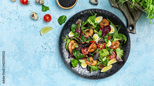 Healthy salad plate. Fresh seafood recipe. cherry tomatoes, cucumber, avocado, eggs and smoked shrimps, mixed greens. Long banner format, top view