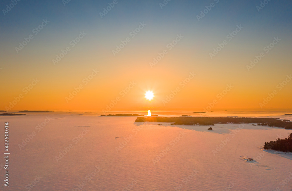 Aerial view of sunrise over the ice-covered Baltic Sea in winter.
