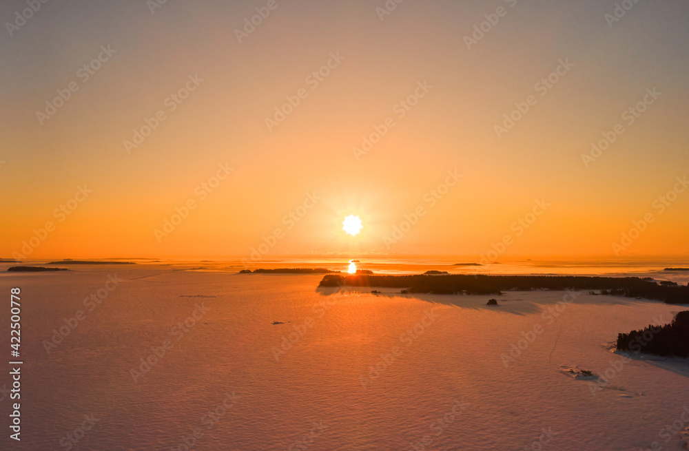 Aerial view of sunrise over the ice-covered Baltic Sea in winter.