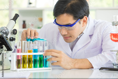 Asian scientist in the laboratory working at lab with test tubes. Asian man scientists researching for Healthcare and biotechnology in laboratory. Concept Production of antiviral drug.