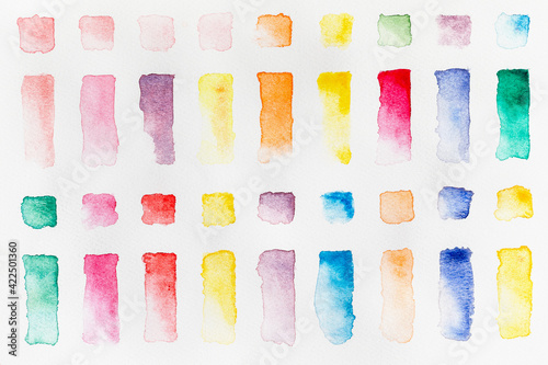 Watercolor paint swatches lined up in a grid on a white background, flatlay horizontal view