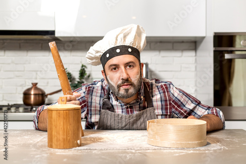 Young Chef with flour hands in his kitchen.