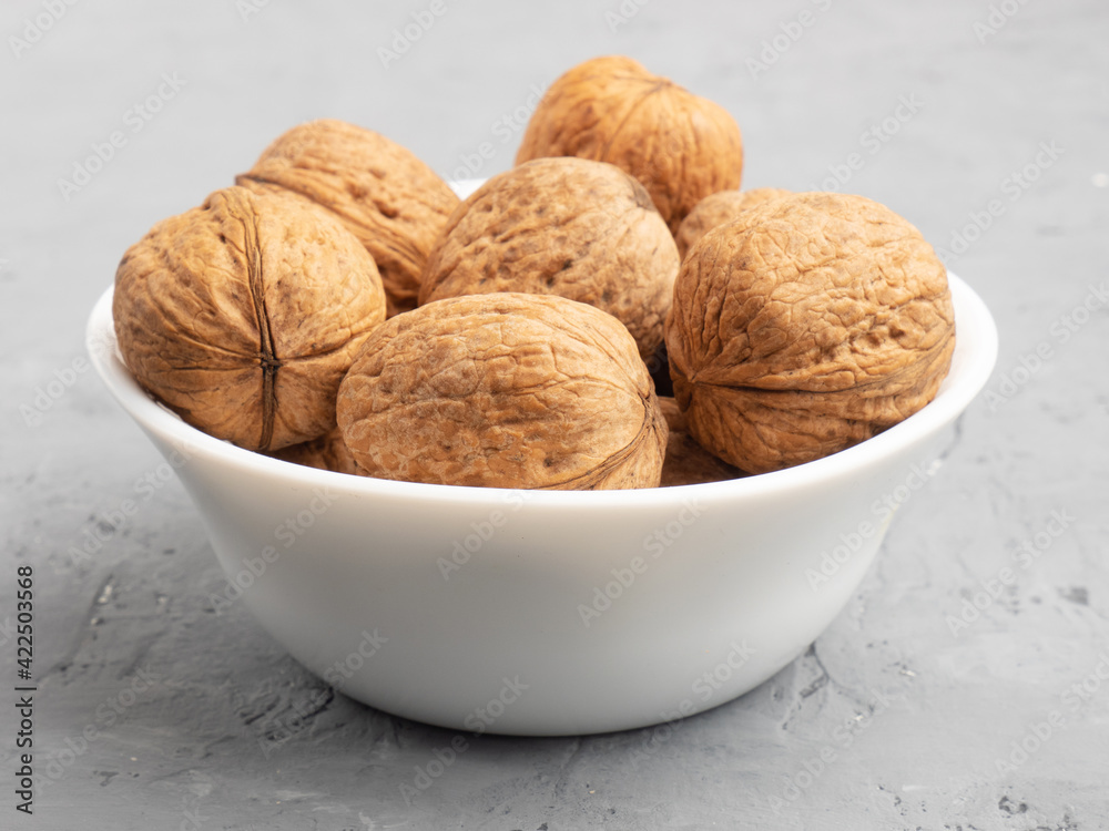 Walnuts in a white bowl on gray concrete background Walnuts in a white bowl on gray concrete background