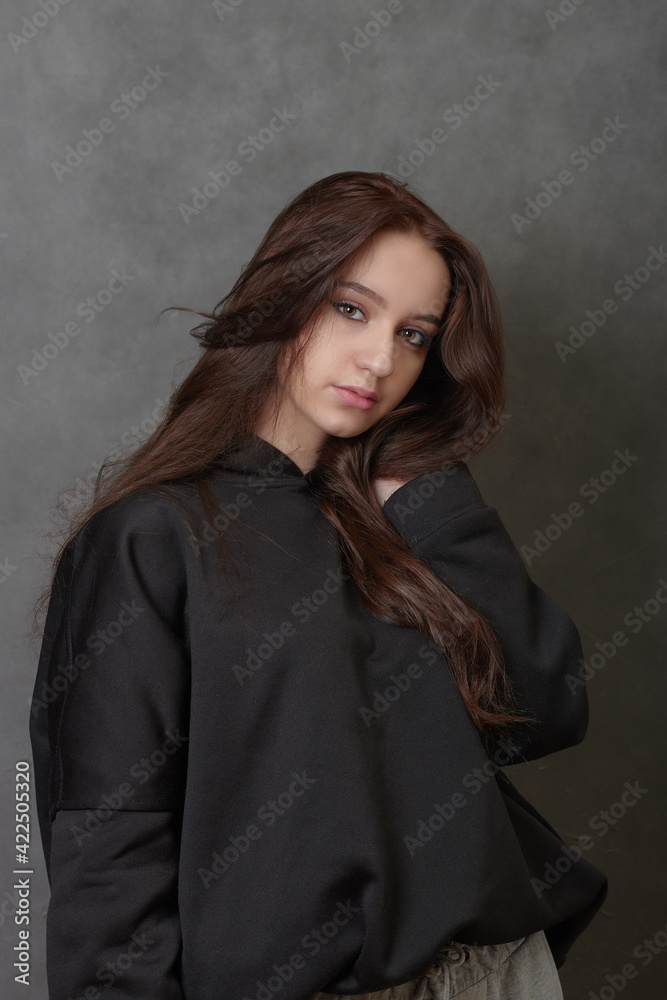 Young long-haired woman wearing black hoody and looking at camera