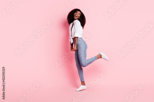 Fototapeta Naklejka Na Ścianę i Meble -  Full size profile photo of gorgeous positive dark skin person raise foot look empty space isolated on pink color background