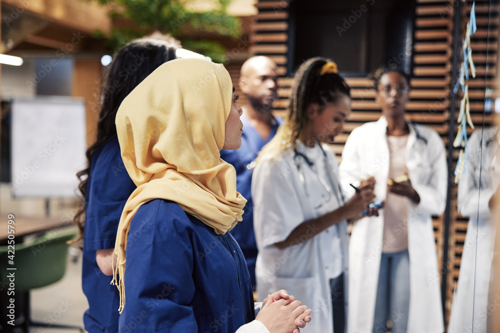 Female Muslim doctor and colleagues brainstorming in a hospital