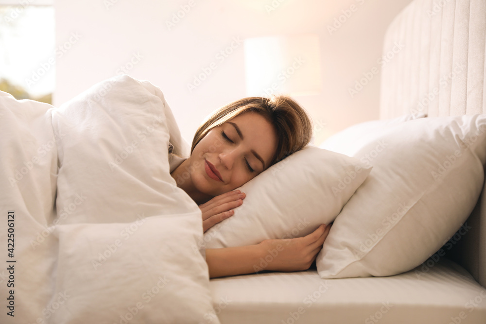 Woman under warm white blanket sleeping in bed indoors Woman under warm white blanket sleeping in bed indoors