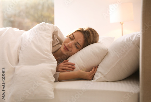 Woman under warm white blanket sleeping in bed indoors