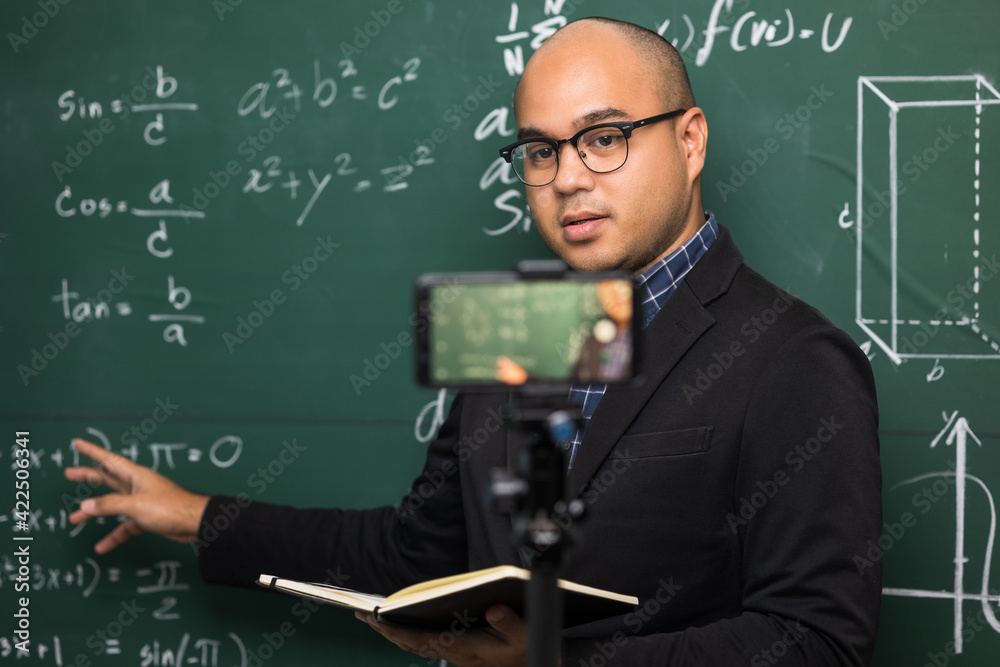 Indian young teacher man teaching online video conference live stream by smartphone. Asian teacher teaching mathematics class webinar online for students learning. Indian young teacher man teaching online video conference live stream by smartphone. Asian teacher teaching mathematics class webinar online for students learning.
