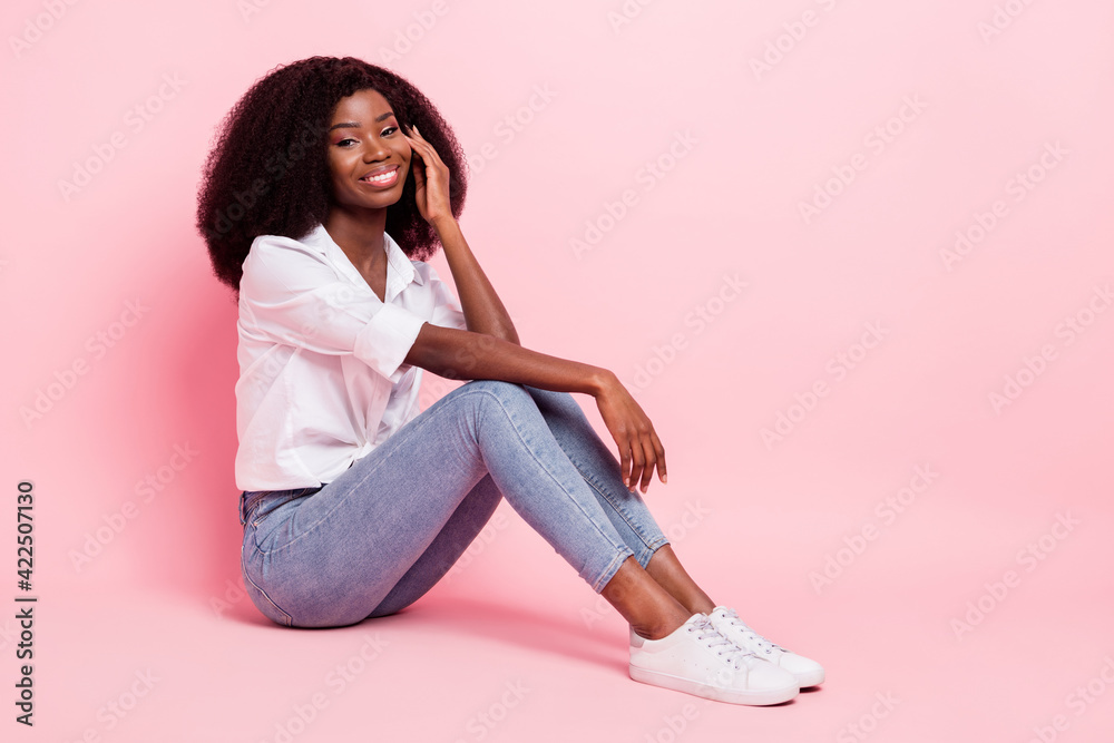 Full size profile photo of nice optimistic brunette hairdo lady sit wear white shirt jeans sneakers isolated on pink color background Full size profile photo of nice optimistic brunette hairdo lady sit wear white shirt jeans sneakers isolated on pink color background