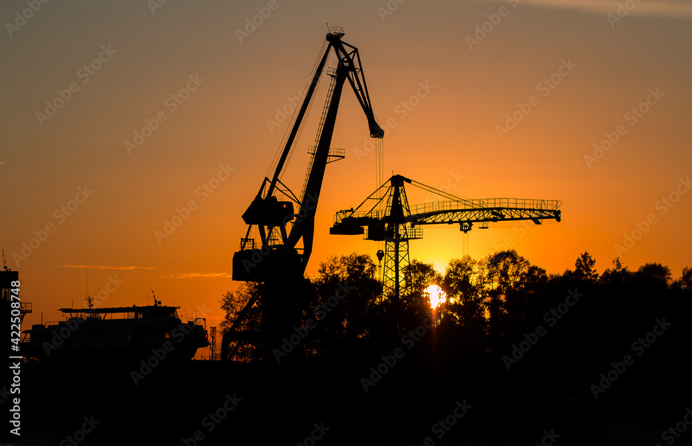 River boat and floating river cranes on the river bank at sunset