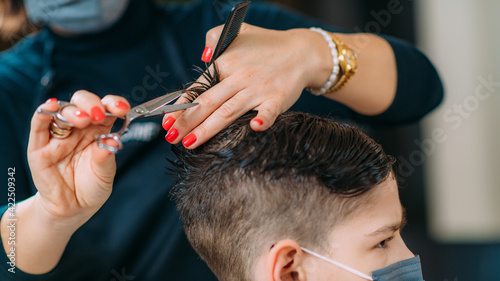 Hairdresser with Protective Mask Cutting Boy's Hair