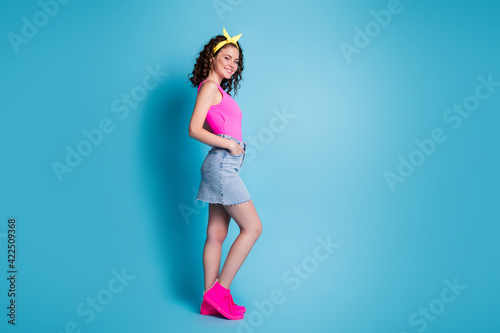 Full body profile side photo of beautiful girl hold hands pockets denim skirt wear yellow headband isolated on blue color background