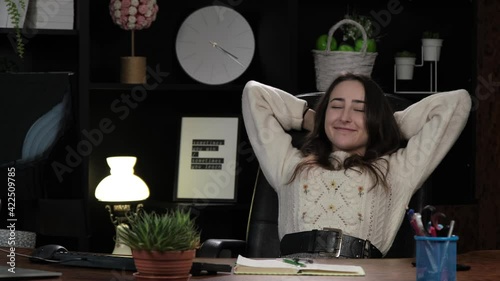 Young business woman worker relax sit at office desk finished computer work put hands behind head in home office. Female closed eyes smiling relaxing, no stress, filling with positive thoughts.