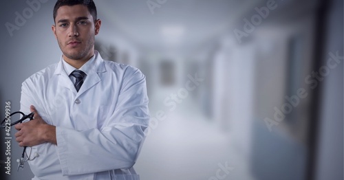Portrait of caucasian male doctor with arms crossed standing at hospital