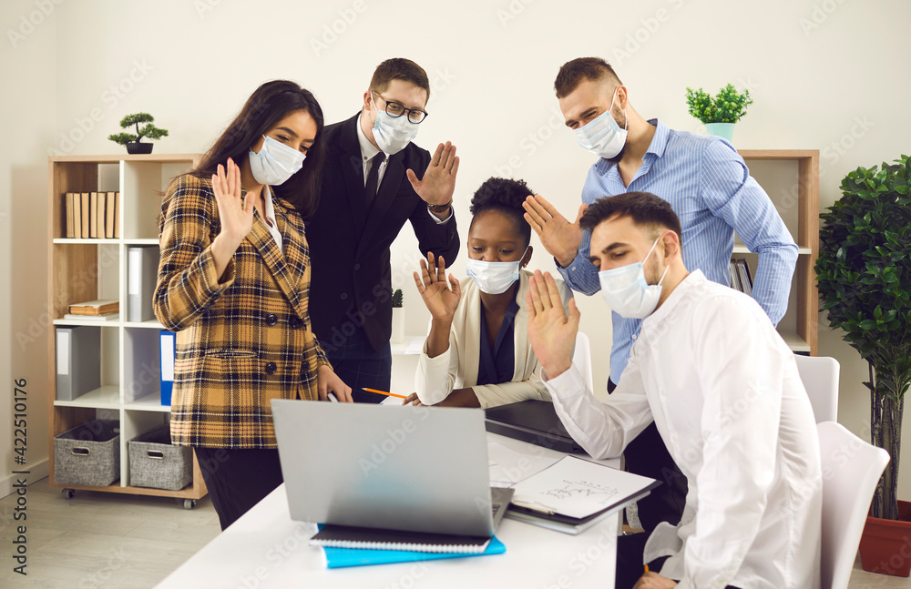 Online meeting, social distancing, business webinar. Diverse interracial coworker team wearing in protective masks to protect from Covid-19 waving hand looking to laptop screen having video conference Online meeting, social distancing, business webinar. Diverse interracial coworker team wearing in protective masks to protect from Covid-19 waving hand looking to laptop screen having video conference