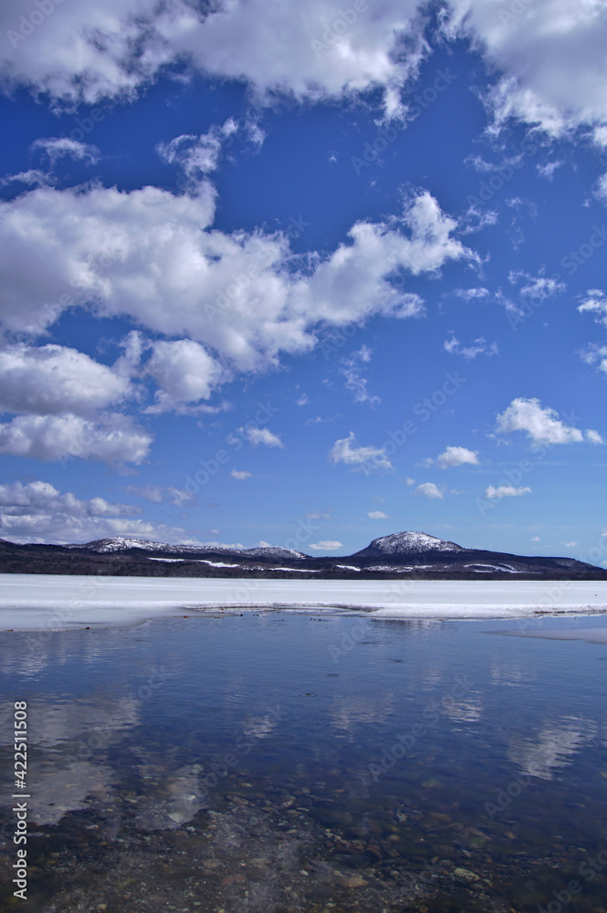 雲の浮かぶ青空と冬の終わりの湖。