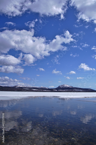 雲の浮かぶ青空と冬の終わりの湖。