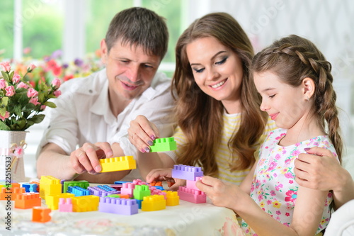 girl with mother and father playing with colorful plastic blocks