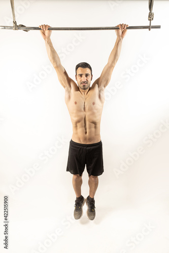 Athlete man doing pull-ups on white background. © robcartorres