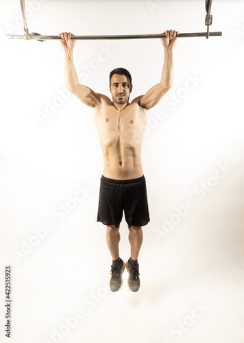 Athlete man doing pull-ups on white background.