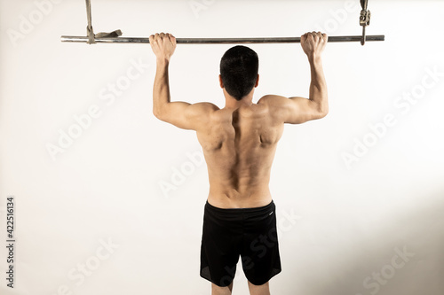 Athlete man doing pull-ups on white background.