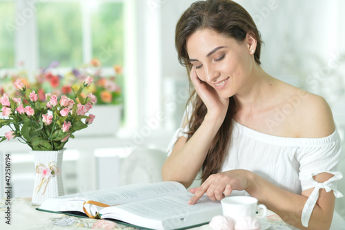 Young attractive woman with book and cup of coffee