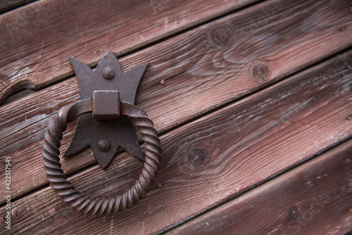 Old metal door handle knocker on a rough wooden background
