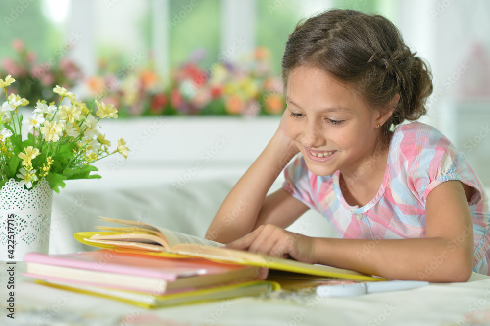 little cute girl reading book at the table at home little cute girl reading book at the table at home