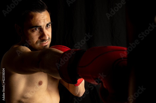 athlete man training with boxing gloves on black background © robcartorres