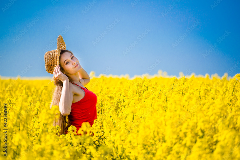 Fototapeta premium Summer portrait of woman in rapeseed. Rural scene with model girl enjoying sun in yellow flowers in field. Concept of joy, happiness and freedom.