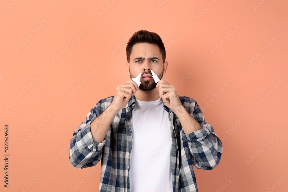 Man using nasal sprays on peach background Man using nasal sprays on peach background