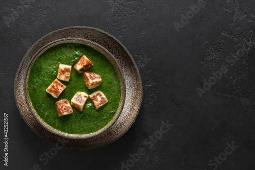 Palak paneer of spinach and cheese isolated on a black background with copy space. Traditional Indian cuisine. Top view.