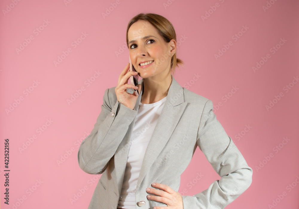 Young beautiful smiling business woman talking on mobile phone isolated over pink background. Young beautiful smiling business woman talking on mobile phone isolated over pink background.