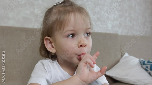 a large portrait of a little girl who sucks her finger in her mouth. Bad habits in children and adolescents.