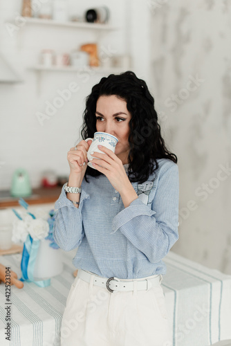 brunette girl in a blue shirt drinks from a mug