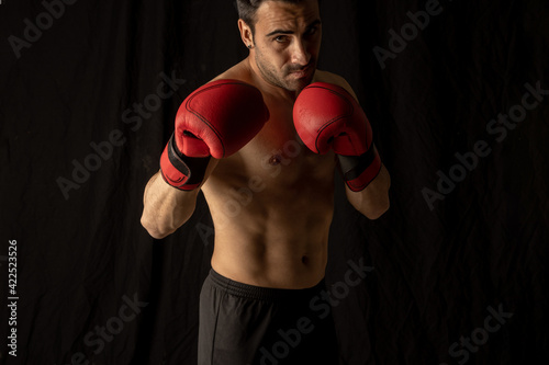 athlete man training with boxing gloves on black background