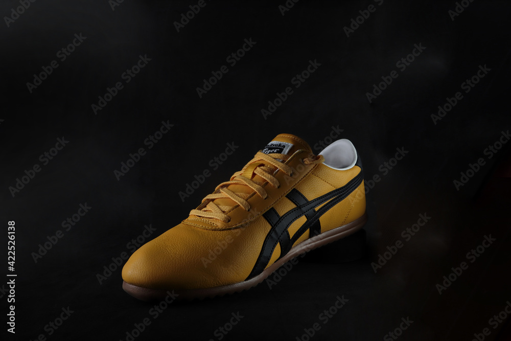 The yellow black Tai Chi Reb Onitsuka Tiger sneaker sport footwear is  displayed on the black display shelf in the Onitsuka Tiger shop in Shinjuku  branch during summer sales foto de Stock