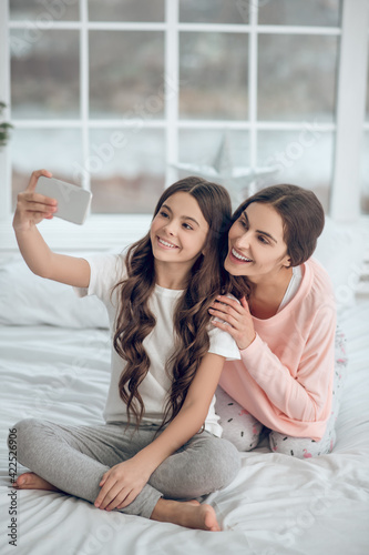 Girl with smartphone in outstretched hand and mom