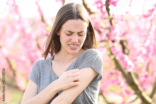 Stressed woman scratching itchy arm after insect bite in a field © PheelingsMedia