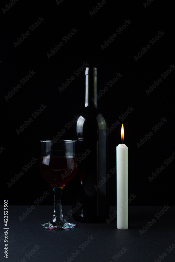 Obraz premium Wine and candle on a dark background. Creative photo of red wine on a black background. Wine by candlelight