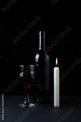 Wine and candle on a dark background. Creative photo of red wine on a black background. Wine by candlelight