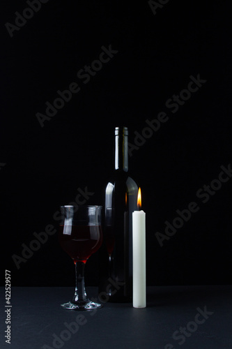 Wine and candle on a dark background. Creative photo of red wine on a black background. Wine and candle smoke