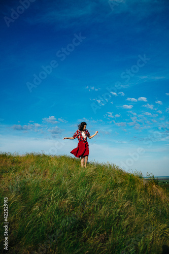 girl in a red skirt enjoys the summer in the field