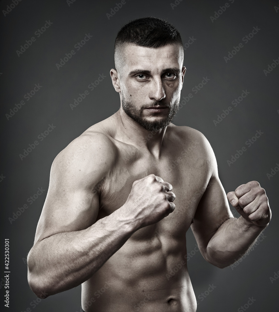 Athletic fighter posing on gray