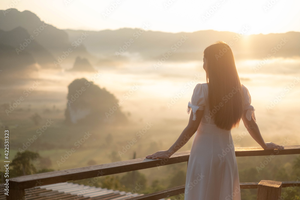 Woman wearing white dress stand and see the mountain view in the morning at phu langka national park,thailand. Summer holiday vacation concept Woman wearing white dress stand and see the mountain view in the morning at phu langka national park,thailand. Summer holiday vacation concept